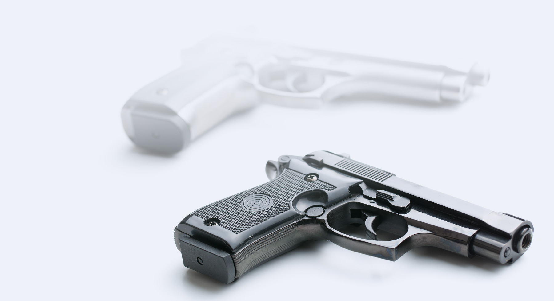 Hand gun on a blank white background with fading shadow in the background.