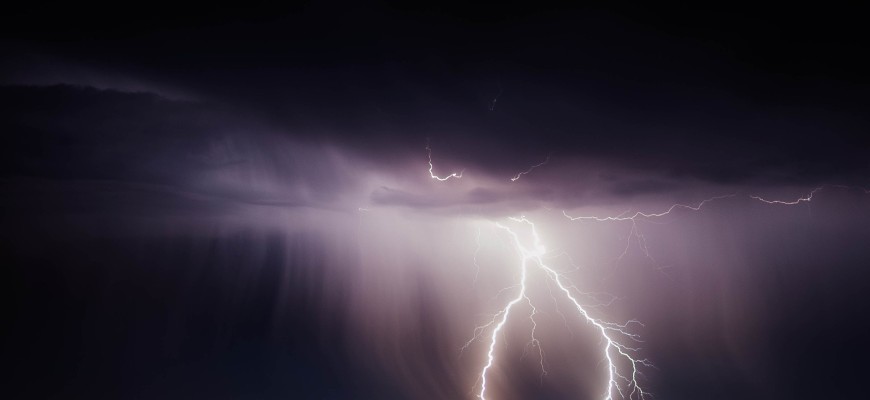 Lightning striking an open field at night.